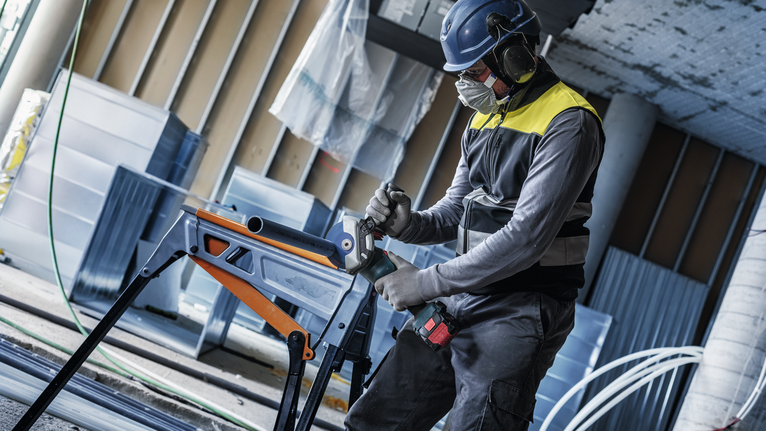 配戴安全設備的人員在工作台上鑽入金屬管。