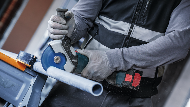 配戴安全設備的人員用圓鋸切割塑膠管。