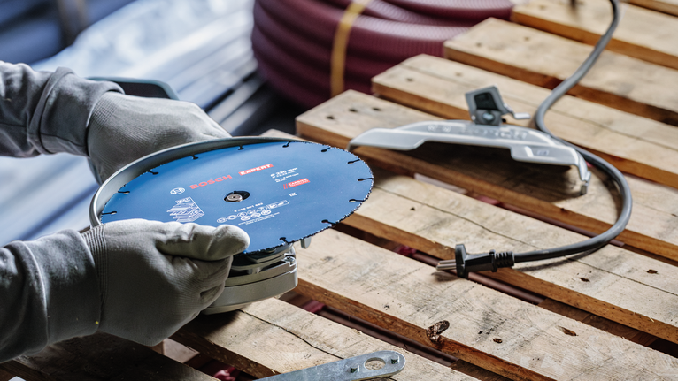 配戴安全設備的人員正在調整木托盤上的電動工具。