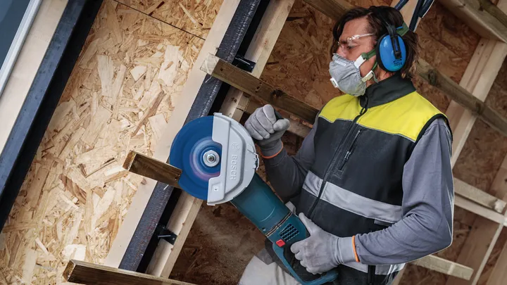 配戴安全設備的人員使用大型圓鋸切割木材。