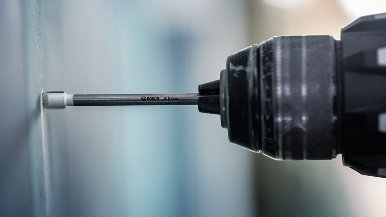 用鑽頭將螺絲旋入牆壁。