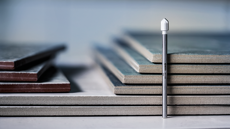 鑽石瓷磚鑽頭直立在堆疊的瓷磚前面。