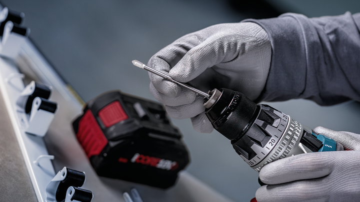 配戴安全設備的人員將鑽頭插入無線電鑽。