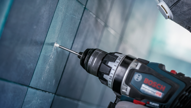 配戴安全設備的人員在磁磚牆上鑽孔。