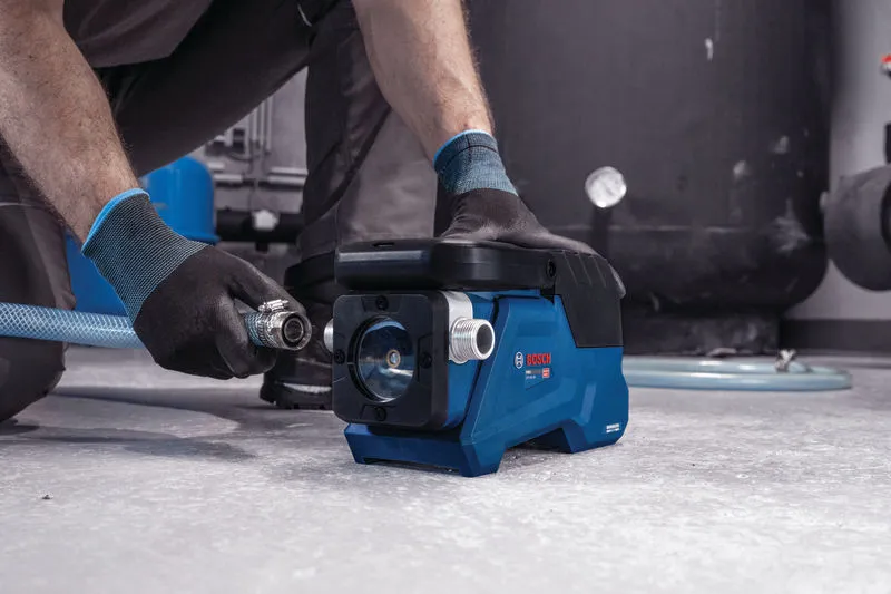 一名穿戴安全裝備的人員將軟管連接到一台小型藍色水泵。