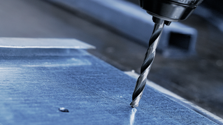 用電鑽在金屬板上鑽孔。