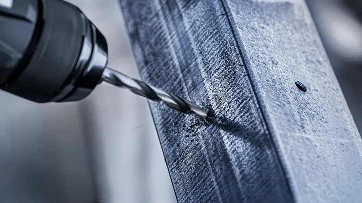 用鑽頭在金屬樑上鑽孔。