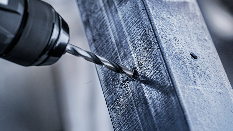 用鑽頭在金屬樑上鑽孔。