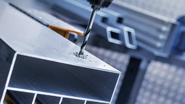 在工業環境中，鑽頭在金屬樑上鑽孔。