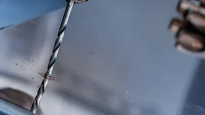 一個人在金屬板上鑽孔。