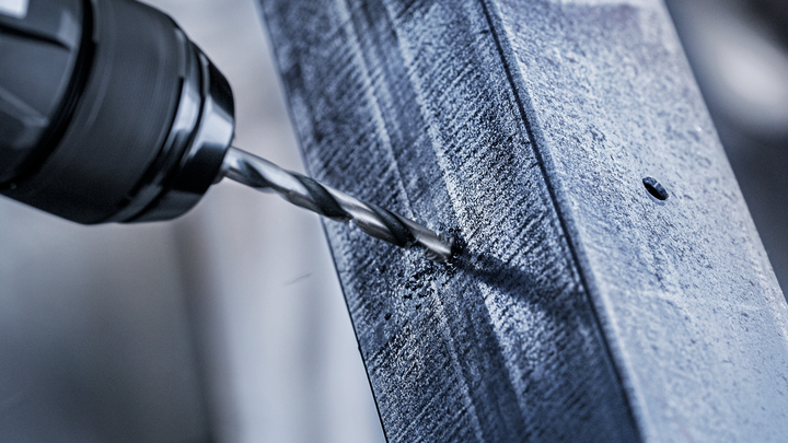 電鑽在金屬樑上鑽出一個洞。