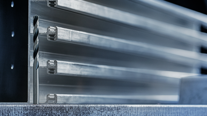 鑽頭垂直放置在堆疊金屬型材前方的金屬表面上。