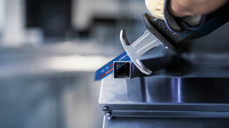 一名配戴安全裝備的人員使用往復鋸切割金屬方管。