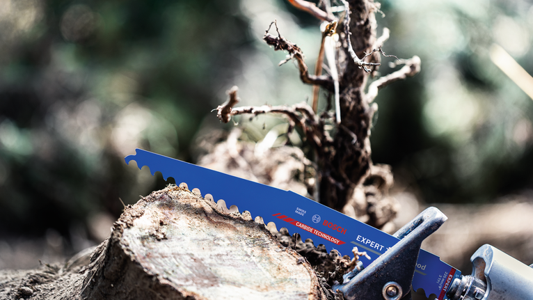 戶外，一把裝有鋸片的電動工具正在切割樹枝。