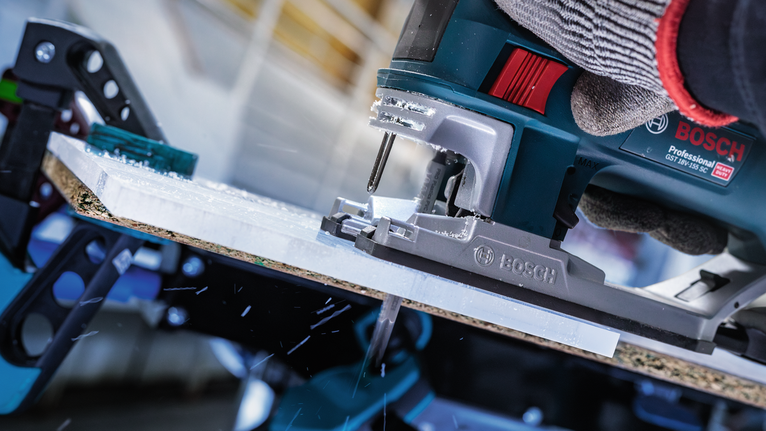 配戴安全裝備的人員操作曲線鋸切割板材。