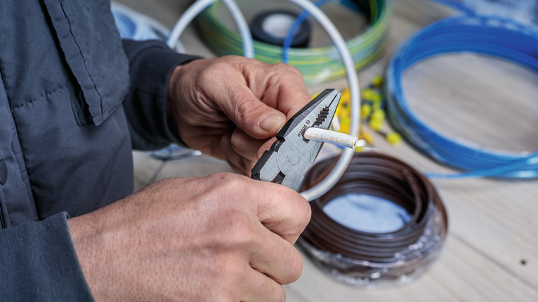 有人用鉗子在盤繞的電纜附近剪斷電線。