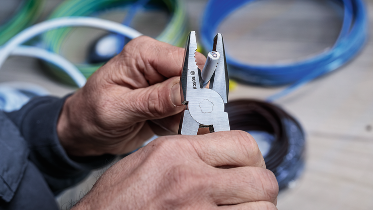 有人用鉗子剝去電線上的絕緣層。