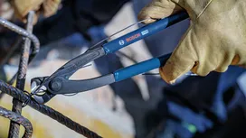 配戴安全裝備的人員使用鉗子剪斷建築用電線。