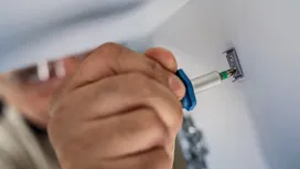 穿戴安全裝備的人員用螺絲起子將金屬支架固定在牆上。