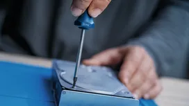 用螺絲起子將螺絲擰緊在金屬裝置上的人。