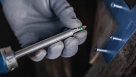 配戴安全裝備的人員手持螺絲起子頭，靠近固定好的金屬支架。