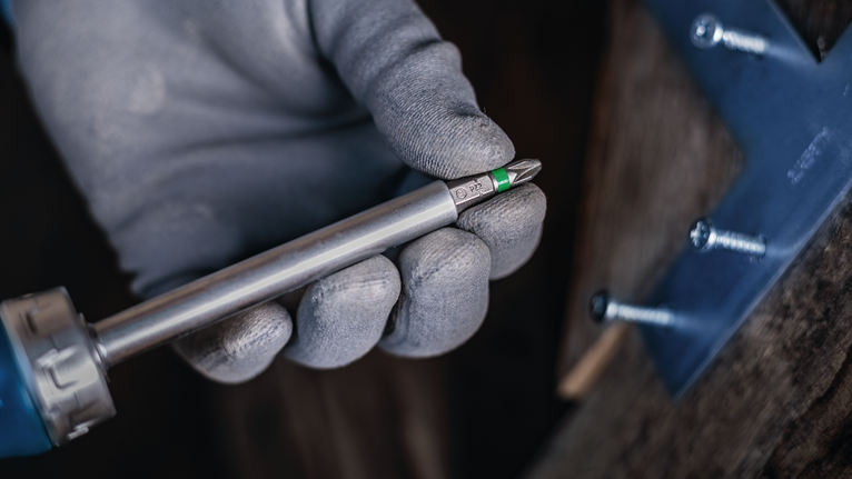 配戴安全裝備的人員手持螺絲起子頭，靠近固定好的金屬支架。