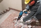 一名配戴安全設備的人員使用拆除工具來破碎地磚。