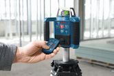 在建築環境中，人員使用遙控器操作雷射調平工具。